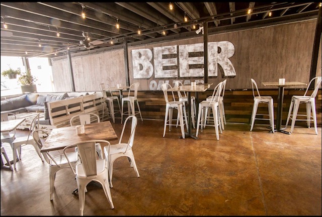 A restaurant with tables and chairs and a sign that says beer on the wall.