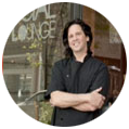 A man standing in front of a restaurant with his arms crossed.